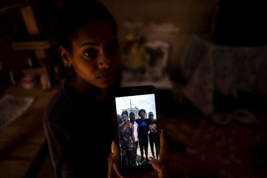 María Carla Milán Ramos muestra una foto en su teléfono de su esposo con sus hermanos, quienes están en prisión acusados de participar en protestas contra el régimen en julio del año pasado, en su casa del barrio La Güinera en La Habana, Cuba, el miércoles 19 de enero de 2022