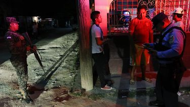 Un soldado protege a un policía que comprueba identificaciones de varios hombres durante una patrulla rutinaria en San Pedro Sula, Honduras, el miércoles 1 de mayo de 2019.&nbsp;