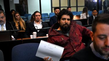 Fernando Sabag Montiel (2º-R), uno de los imputados por el intento de asesinato de la exvicepresidenta argentina Cristina Fernández de Kirchner, muestra una libreta que dice Me tienen como rehén durante el juicio en el juzgado de Comodoro Py, en Buenos Aires.