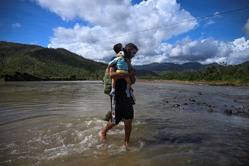 Hombre camina entre las agua con un bebé en brazos tras el paso del huracán Melissa. Cuba.&nbsp;