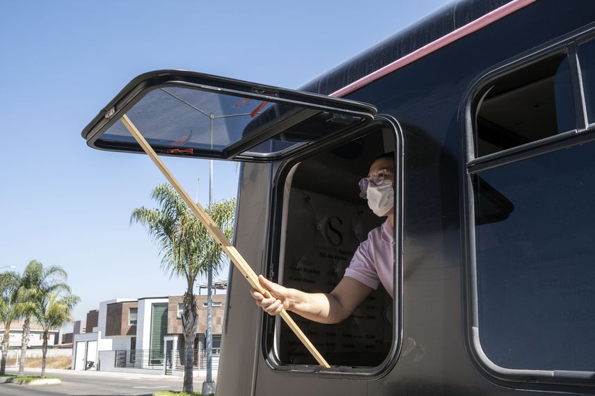 Una mujer abre una ventana en su sal&oacute;n de belleza m&oacute;vil en Tijuana, M&eacute;xico.