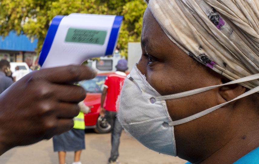 Una mujer, con mascarilla para protegerse del coronavirus, se somete a un control de temperatura antes de entrar a una tienda de comestibles, en el vecindario de Tembisa, Johannesburgo, Sud&aacute;frica, el 19 de mayo de 2020.&nbsp;