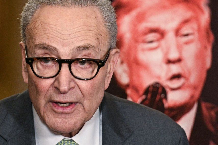 El líder de la minoría del Senado de Estados Unidos Chuck Schumer, demócrata de Nueva York, se encuentra junto a un cartel que muestra una imagen del presidente Donald Trump, mientras habla con la prensa tras una reunión a puerta cerrada con los senadores demócratas en el Capitolio, en Washington, DC, el 3 de marzo de 2026.