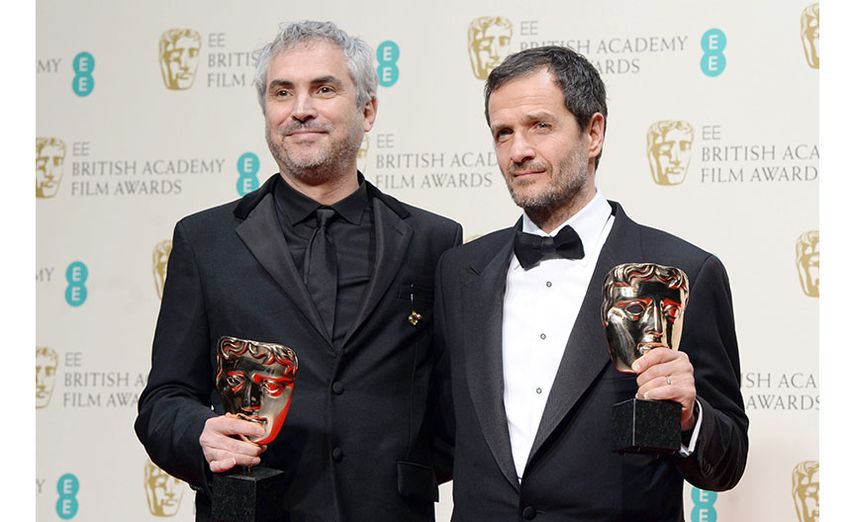 El director mexicano Alfonso Cuarón y el productor británico David Heyman posan para la prensa tras recibir los premios por la película. (EFE)