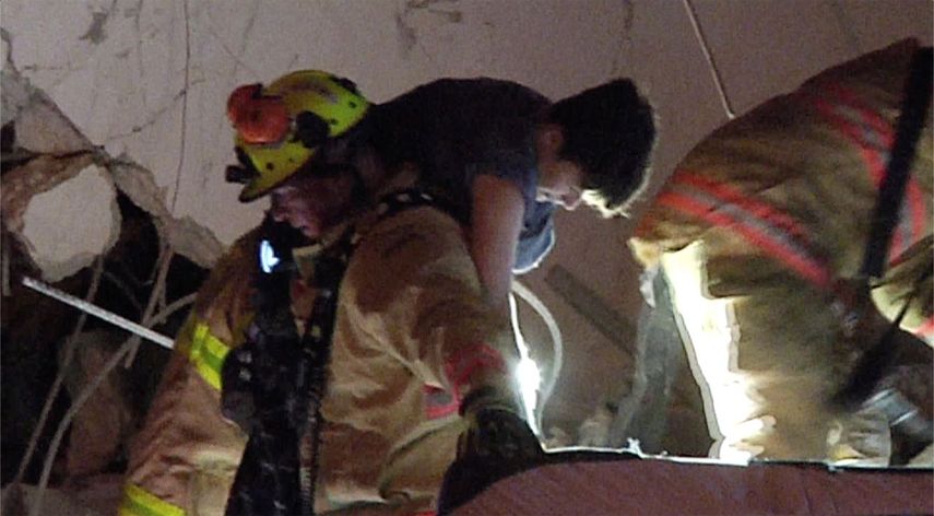 Imagen tomada de un video proporcionado por ReliableNewsMedia de bomberos rescatando a un sobreviviente del condominio Champlain después de que se derrumbara parcialmente en Surfside, Florida.