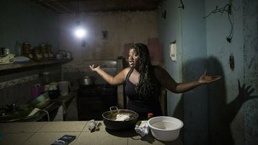 En esta imagen del 14 de febrero de 2019, Dugleidi Salcedo se queja con una vecina sobre el alto precio de los alimentos mientras prepara arepas para sus tres hijos en su cocina en el vecindario de Petare, en Caracas. 