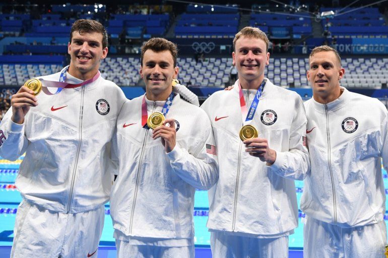 Los medallistas de oro de EEUU Zach Apple, Blake Pieroni, Bowen Becker y Caeleb Dressel posan con sus medallas al salir de la piscina después de la final del evento masculino de natación de relevos 4x100m estilo libre durante los Juegos Olímpicos de Tokio 2020