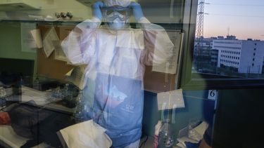 El doctor Giovanni Passeri utiliza el reflejo de una ventana abierta para comprobar que tiene bien colocado el equipo de protecci&oacute;n, antes de iniciar su turno de noche en la unidad de COVID-19 del hospital Maggiore de Parma.&nbsp;