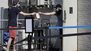 Foto tomada el 26 de mayo del 2020 del empleado de una tienda de marihuana entregándole un paquete a un cliente en Brookline, Massachusetts. 