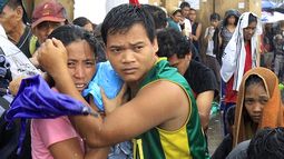 Una pareja protege a su bebe de la lluvia mientras espera un vuelo para ser evacuados en Tacloban el martes 12 de noviembre del 2013. (AP)