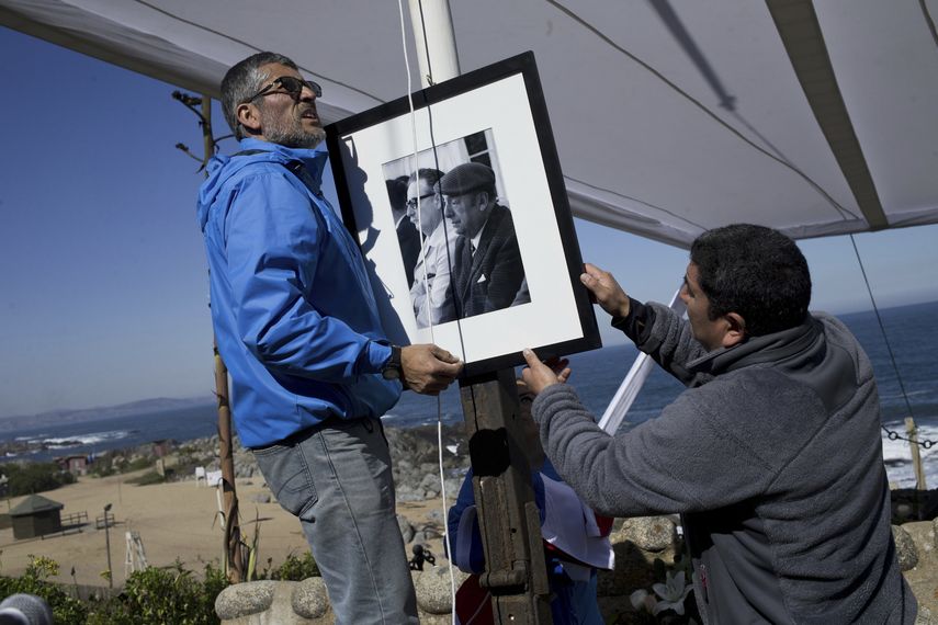 Trabajadores colocan un retrato del difunto poeta chileno ganador del Premio Nobel de Literatura Pablo Neruda con el expresidente Salvador Allende en la tumba del bardo después de que lo enterraran nuevamente en Isla Negra, Chile, el 26 de abril de 2016. Expertos podrían esclarecer la causa de muerte del escritor.