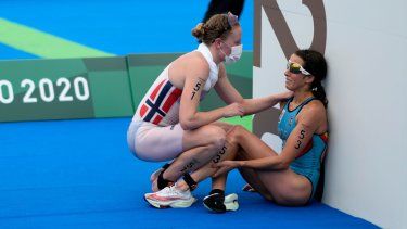 La belga Claire Michel recibe ayuda de la noruega Lotte Miller al finalizar la competencia de triatlón femenino de los Juegos Olímpicos, el 27 de julio de 2021, en Tokio.&nbsp;