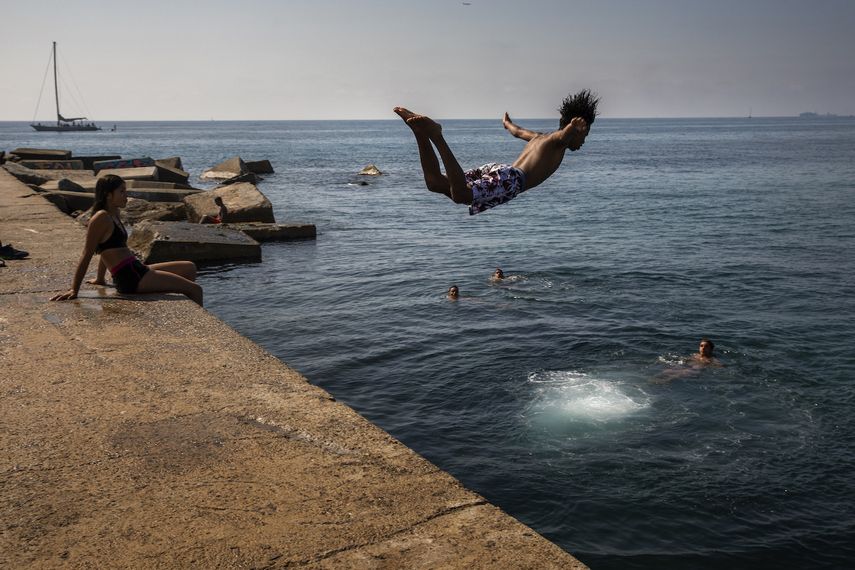 Esta foto de archivo del jueves 25 de julio del 2019 resalta a un niño lanzándose al mar en una playa de Barcelona, España. 