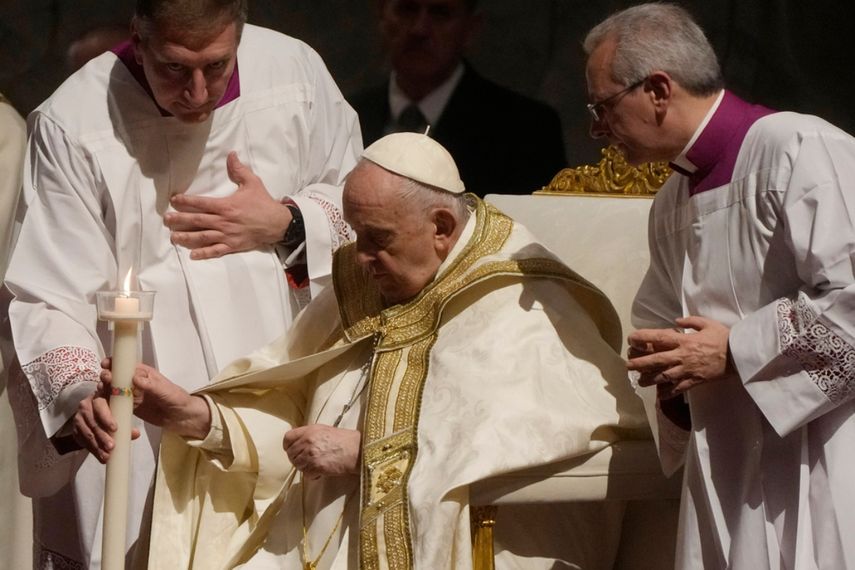 El papa Francisco sostiene un cirio al presidir un oficio de vigilia pascual en la Basílica de San Pedro.