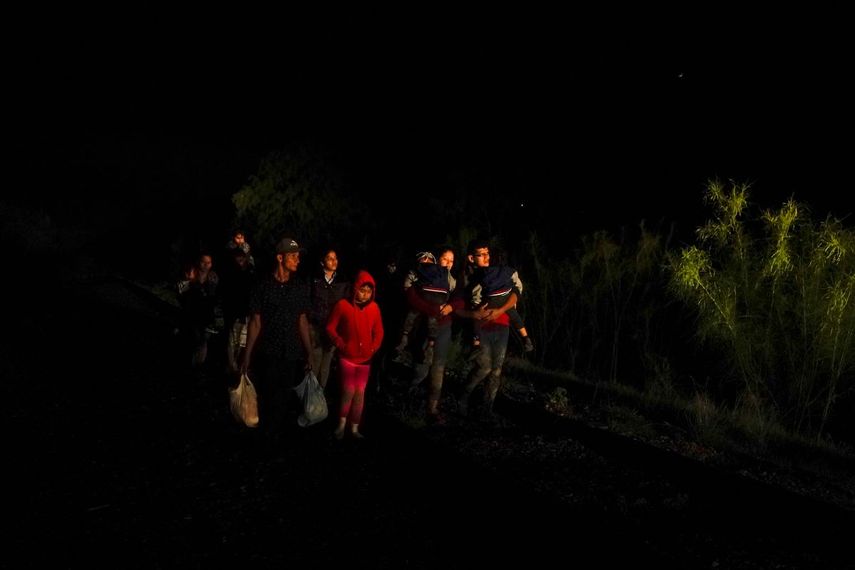 Un grupo de personas con hijos en sus brazos llega a un centro de procesamiento de migrantes que quieren asilarse en EEUU el 12 de mayo del 2021 en La Joya, Texas.