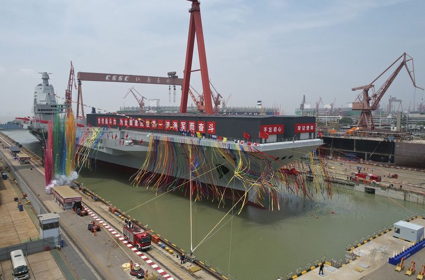 En esta imagen distribuida por la agencia noticiosa Xinhua, humo y cintas de colores conmemoran la botadura del tercer portaaviones de China, bautizado como Fujian, en Shanghái, el 17 de junio de 2022.