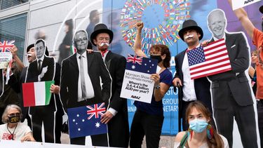 Activistas que sostienen imágenes en cartón del presidente estadounidense Joe Biden, el primer ministro australiano Scott Morrison y el premier italiano Mario Draghi protestan frente a la sede del Fondo Monetario Internacional durante las reuniones anuales entre el FMI y el Banco Mundial, el miércoles 13 de octubre de 2021, en Washington.