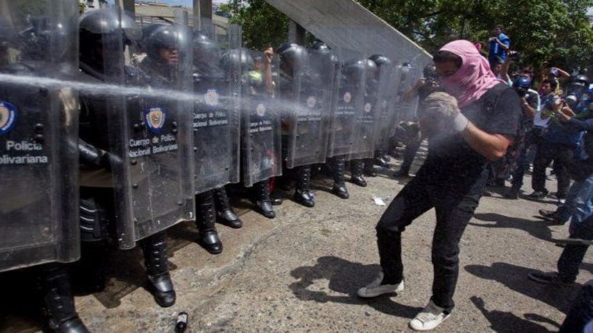 Un oficial de la Policía Nacional Bolivariana rocía aerosol pimienta sobre un manifestante durante enfrentamientos registrados en la Universidad Central de Caracas.&nbsp;
