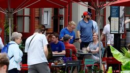Un empleado atiende a clientes en una terraza de un restaurante.