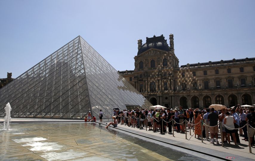 Los visitantes hacen cola en la entrada de la pirámide del museo del Louvre en París el 17 de junio de 2022.