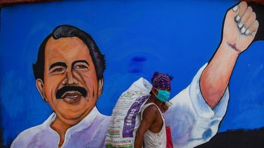 Un desamparado usa una máscara facial para protegerse del nuevo coronavirus, COVID-19, mientras camina junto a un mural con la imagen del dictador nicaragüense Daniel Ortega, en Managua el 9 de abril de 2020.