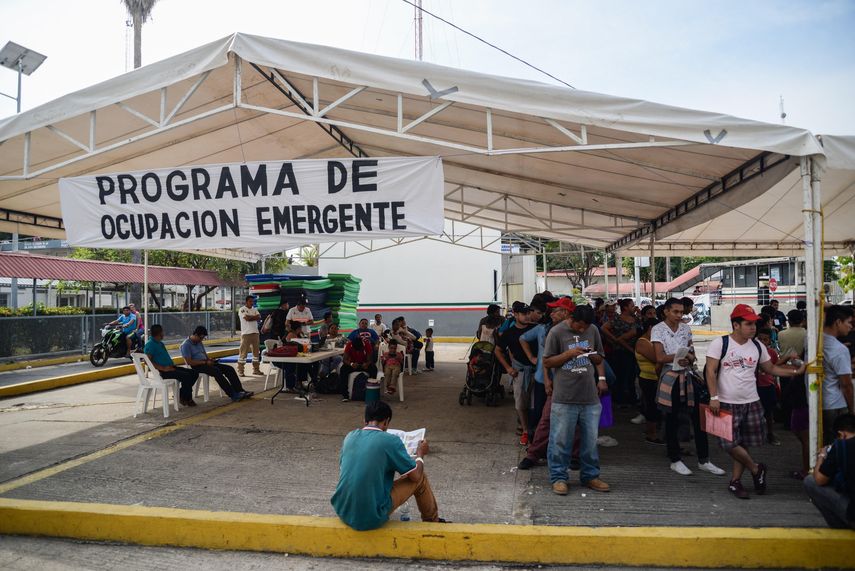 Migrantes hondureños que han decidido acogerse a la tarjeta humanitaria, esperan en el puente que cruza el río Suchiate para ingresar a México.