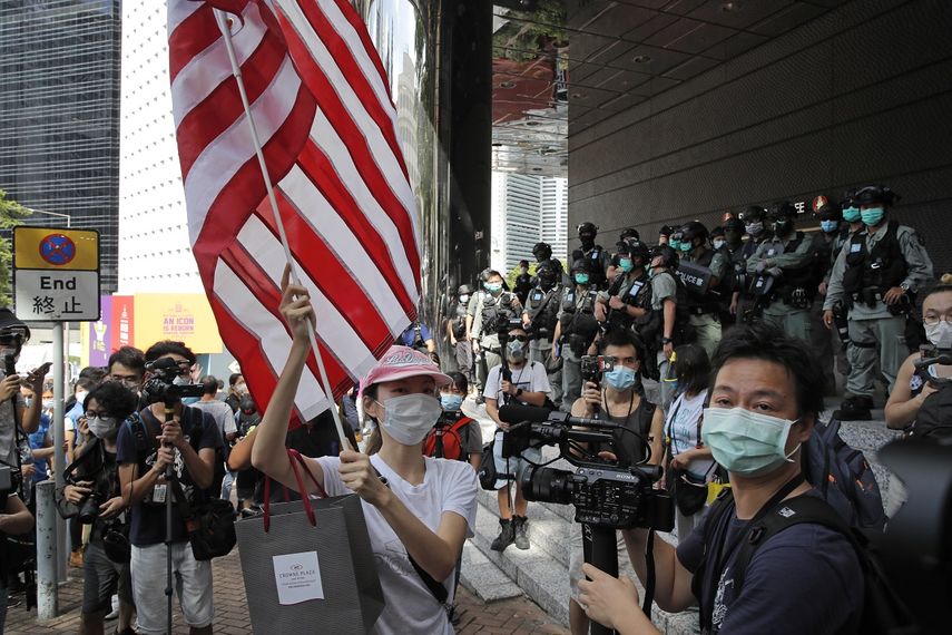 En esta imagen de archivo del 4 de julio de 2020, una mujer lleva una bandera estadounidense ante el consulado de Estados Unidos en Hong Kong.&nbsp;