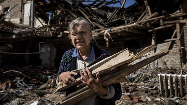 Una mujer recopila leña para calentarse en una escuela destruida que sirvió de base a las fuerzas rusas, en una zona recuperada recientemente por el ejército ucraniano a las afueras de Izium, Ucrania, el 19 de septiembre de 2022.&nbsp; 