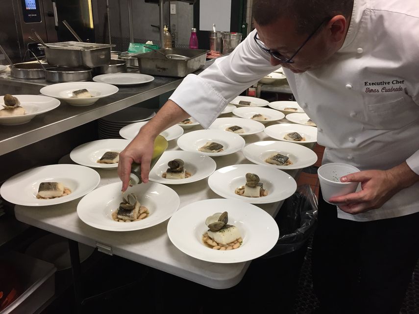 El chef Tomás Cuadrado deposita unas gotas de aceite oliva al estofado de alubias, con bacalao y almejas del Carril al vapor.