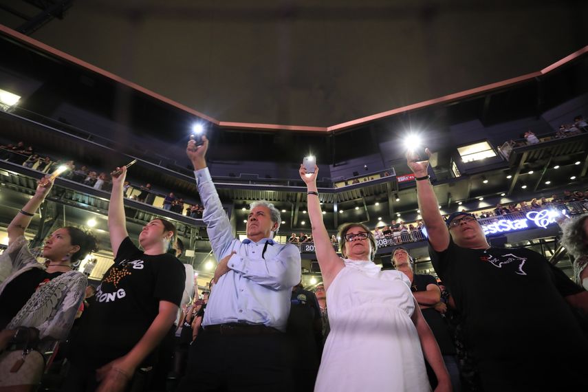 Gente sostiene sus celulares al leerse los nombres de los fallecidos en el tiroteo del 3 de agosto en una ceremonia de recuerdo a las víctimas en el Southwest University Park, en El Paso, Texas, el 14 de agosto de 2019.&nbsp;