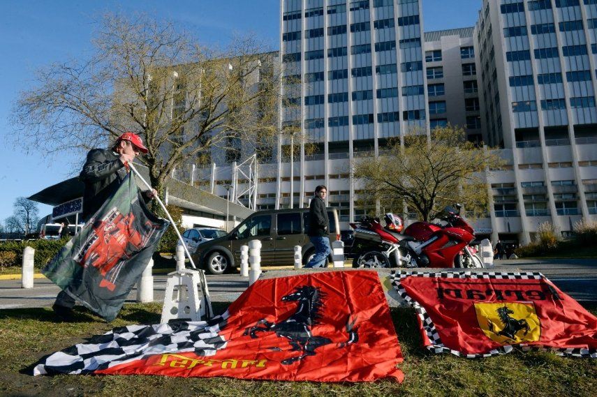 Un aficionado muestra banderas de Ferrari el 30 de diciembre de 2013 frente al Centro Hospitalario Universitario de Grenoble, en los Alpes franceses, donde Michael Schumacher, el siete veces campeón del mundo de Fórmula 1 retirado, se encontraba en estado crítico tras sufrir un accidente de esquí fuera de pista. El legendario piloto alemán, que cumplirá 45 años a finales de semana, fue rescatado en helicóptero desde una montaña en la lujosa estación de Méribel el día anterior tras caerse y golpearse la cabeza contra una roca mientras esquiaba fuera de pista con su hijo de 14 años.