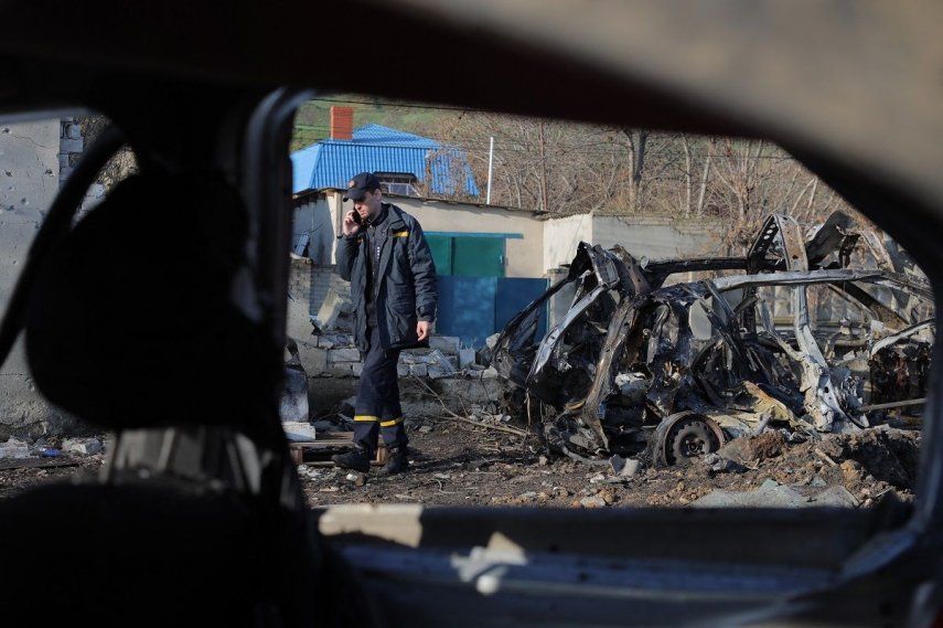 Un agente de la policía ucraniana habla por teléfono móvil mientras pasa junto a un coche destrozado en el aparcamiento de una estación de servicio tras un ataque aéreo en Odesa el 21 de noviembre de 2025, en plena invasión rusa de Ucrania.&nbsp; &nbsp;