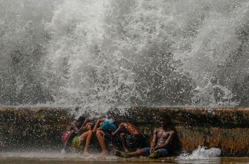 Jóvenes se agachan detrás del malecón mientras juegan con las olas causadas por el paso del huracán Milton por el Golfo de México, en La Habana, Cuba, el miércoles 9 de octubre de 2024. &nbsp;