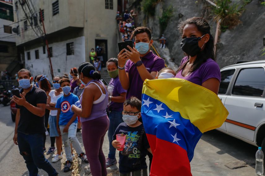 Varias personas usando tapabocas ven pasar la imagen del Nazareno en la Semana Santa, en Caracas, Venezuela, durante la cuarentena por el coronavirus COVID-19.