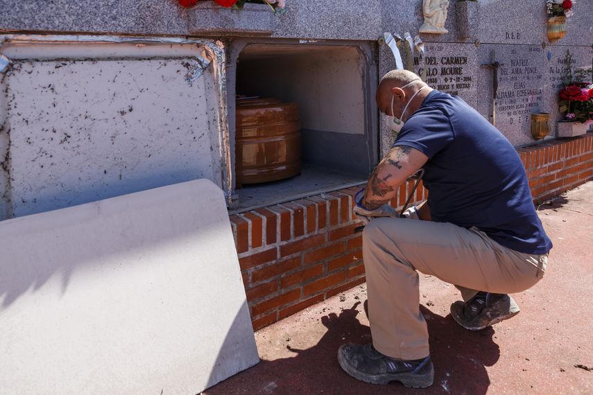Un empleado de la morgue con una m&aacute;scara facial coloca el ata&uacute;d de una v&iacute;ctima de coronavirus COVID-19 en un nicho durante un entierro en el cementerio de Fuencarral en Madrid el 29 de marzo de 2020.&nbsp;
