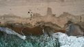 Esta fotografía tomada con un dron muestra desde las alturas a bañistas mientras trabajadores con trajes protectores continúan limpiando las partes contaminadas con crudo en la playa de la localidad de Huntington Beach, California. Esta fotografía tomada con un dron muestra desde las alturas a bañistas mientras trabajadores con trajes protectores continúan limpiando las partes contaminadas con crudo en la playa de la localidad de Huntington Beach, California.