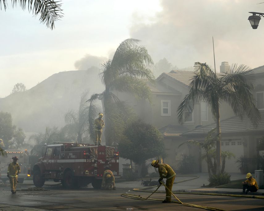 Varios bomberos limpian la calle de una urbanización afectada por el&nbsp;incendio en Anaheim Hills, California.&nbsp;&nbsp;