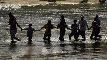Migrantes forman una cadena humana para cruzar el Río Bravo desde México a Estados Unidos, el 21 de septiembre de 2023, en Eagle Pass, Texas.&nbsp; 