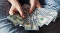 Una mujer muestra billetes de dólar estadounidense. Una mujer muestra billetes de dólar estadounidense.