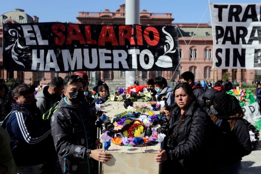 Integrantes de organizaciones sociales realizan un simulacro de velorio por la muerte del salario, en referencia a los salarios que no están a la altura de la inflación, frente al palacio de gobierno Casa Rosada en Buenos Aires, el 19 de agosto de 2022.