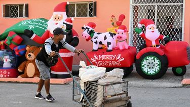 Un hombre empuja un carrito frente a una casa con decoraciones navideñas inflables en La Habana el 23 de diciembre de 2025.