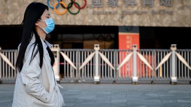 Una mujer que usa una m&aacute;scara facial como medida preventiva contra el nuevo coronavirus COVID-19 camina en el parque ol&iacute;mpico de Beijing el 23 de marzo de 2020.