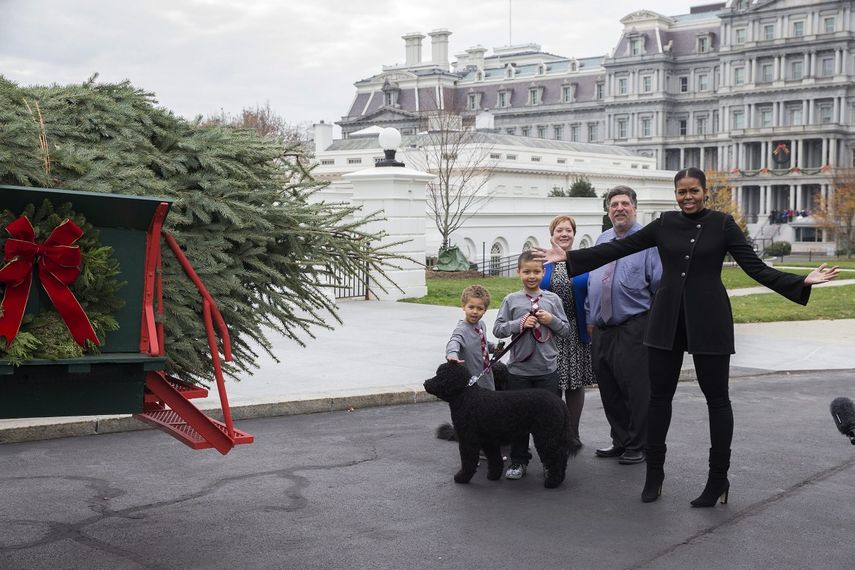 Con abrigo negro y pantalones del mismo color, Michelle Obama salió a recibir al árbol en compañía de dos de sus sobrinos, Austin y Aaron Robinson
