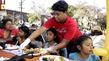 Fotografía de archivo fechada en noviembre de 2017 de una voluntaria entregando comida a un grupo de personas sin hogar en Los Ángeles, California.