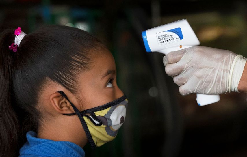 Un trabajador de la salud toma la temperatura de una ni&ntilde;a para ayudar a aplanar la curva de contagios del nuevo coronavirus en el mercado Central de Abastos en Ciudad de M&eacute;xico el jueves 18 de junio de 2020.