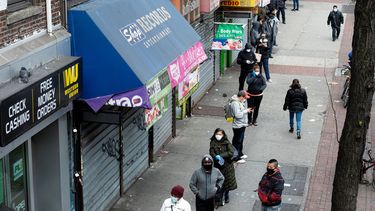 Personas usan máscaras mientras hacen cola para ingresar a una tienda que ofrece servicios de cambio de cheques, el 14 de abril de 2020 en la ciudad de Nueva York.