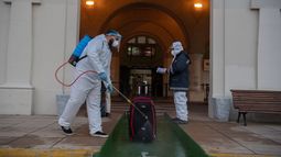 Un empleado en traje de protecci&oacute;n desinfecta el equipaje de un pasajero frente a la terminal de la empresa argentina de servicios de ferry Buquebus en el puerto de Montevideo, el 10 de julio de 2020, en medio de la nueva pandemia de coronavirus.