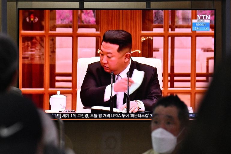 La gente se sienta cerca de una pantalla que muestra una transmisión de noticias en una estación de tren en Seúl el 12 de mayo de 2022, del líder de Corea del Norte, Kim Jong Un, quitándose una máscara facial en la televisión para ordenar cierres en todo el país después de que el Norte confirmara sus primeros casos de COVID-19  
