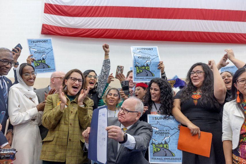 Partidarios, políticos y autores de la ley celebran luego de que el gobernador de Minnesota, Tim Walz (centro), promulga la ley “Licencia de conducir para todos”, en St. Paul, Minnesota, el 7 de marzo de 2023.&nbsp;