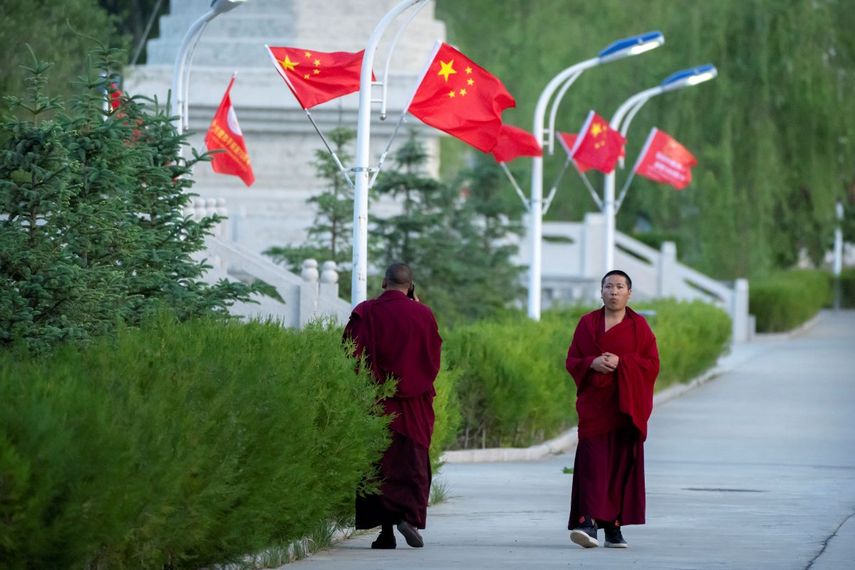 Dos monjes caminan por una calle con banderas chinas en Lhasa, capital de la Región Autónoma Tibetana de Chin